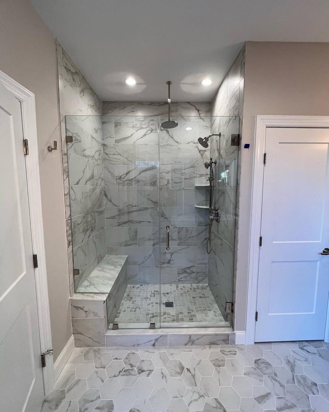 Walk-in shower with marble or wall tile, a bench and glass door.